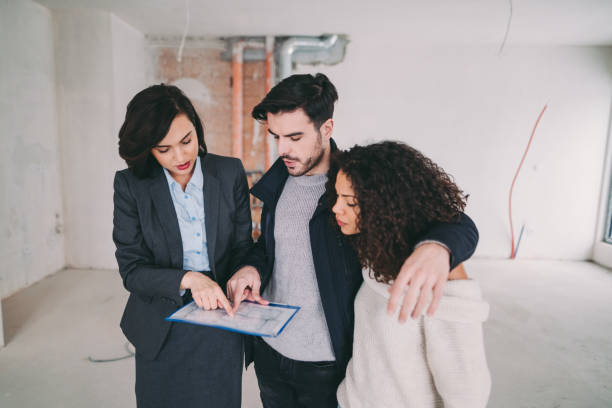 Agent immobilier qui présente un bien en construction à un jeune couple